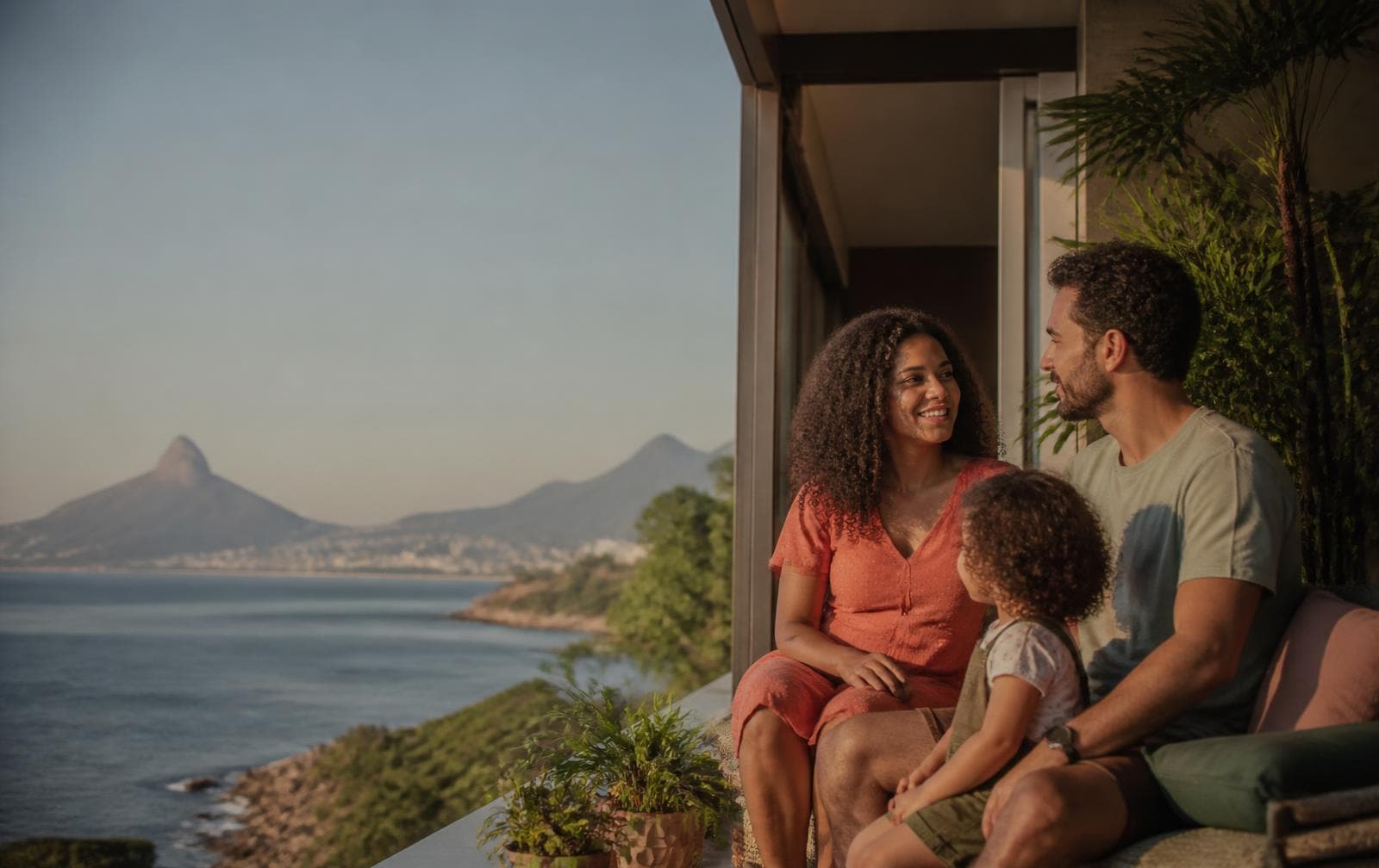 Família reunida na varanda de casa diante do mar no fim da tarde